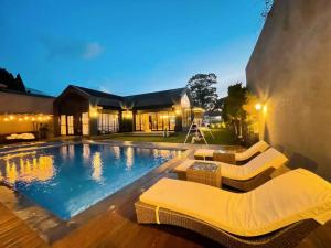 a swimming pool with two chairs and a house at De Black Challet Villa in Tagalbato