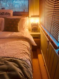 a bedroom with a bed and a night stand with a window at The Bus In The Woods in Belturbet