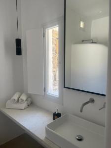 ein weißes Bad mit einem Waschbecken und einem Fenster in der Unterkunft Mykonos Drops in Platis Gialos