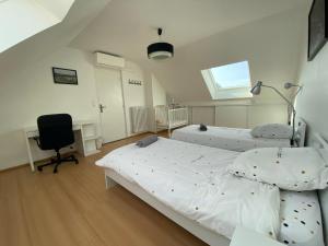 a bedroom with two beds and a desk and a chair at La Maison du Canal d’Ay in Ay