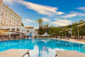 a swimming pool at a hotel with tables and chairs at Minura Cala Galdana & Apartamentos d'Aljandar in Cala Galdana
