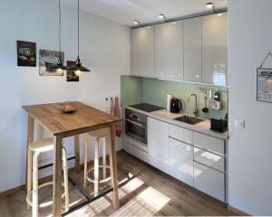 una cucina con mobili bianchi e un tavolo di legno di Chalet Oasis - Your Alpine Hideaway a Bürglen