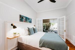 Un dormitorio con una gran cama blanca y una ventana. en Kialla Cottage - An Idyllic Country Escape, en Mudgee