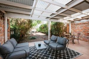 un patio con 2 sofás y una mesa con una mesa en Kialla Cottage - An Idyllic Country Escape, en Mudgee