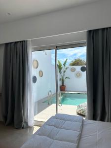 ein Schlafzimmer mit einem großen Fenster und einem Pool in der Unterkunft Mykonos Drops in Platis Gialos