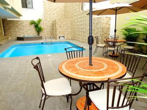 un patio con mesa, sillas y piscina en Hotel Marvento Suites en Salinas