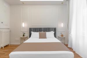 una camera bianca con un grande letto con due tavoli di Montello Suites Foresteria Lombarda a Milano