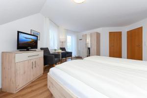 a white bedroom with a large bed and a desk at Hotel-Pension Marlies in Neuharlingersiel