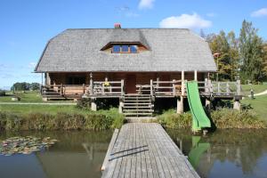 a log cabin with a dock and water lilies at Brīvdienu māja Polīši in Kuldīga