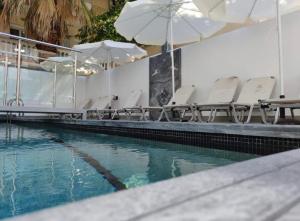 a swimming pool with white chairs and umbrellas at AquaLux Apartment in Kallithea Halkidikis