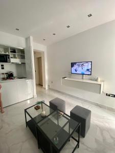 sala de estar con mesa de cristal y TV en la pared en AquaLux Apartment, en Kallithea Halkidikis