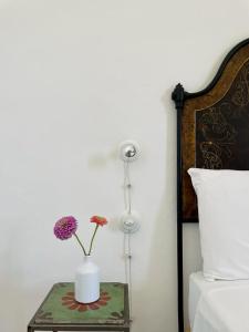 a table with a vase with flowers on it next to a bed at Galeta Masseria in Nardò
