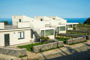 a view of a house with the ocean in the background at Paolimura Resort , Apartment & Spa in Aci Catena +105 photos