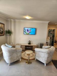 a living room with two chairs and a table at Haus Merwe Self Catering in Cape Town