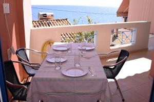 a table with plates and glasses on a balcony at thalassa home in Nikiana