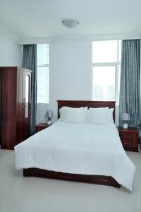a bedroom with a large white bed and two windows at Comfort in Sharjah
