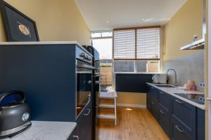 una cocina con armarios azules y una gran ventana en Welcome in - Appartement midden in het centrum met dakterras, en Vlissingen
