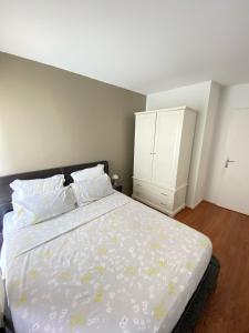 a bedroom with a bed and a white cabinet at Appartement lumineux 4 personnes in Enghien-les-Bains