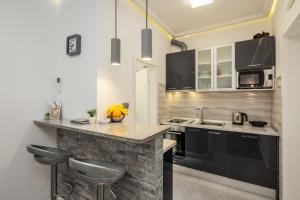 una cocina con armarios negros y una barra con taburetes en Centrino Apartment, en Split