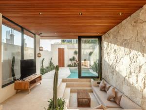 Una sala de estar con un sofá y un televisor. en Blacksand Villas Echo Beach Canggu B4, en Canggu