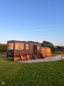 ein winziges Haus mit einem Tisch und Stühlen auf einem Feld in der Unterkunft Tiny House La Cavalerie, au milieu des chevaux ! in Annouville-Vilmesnil