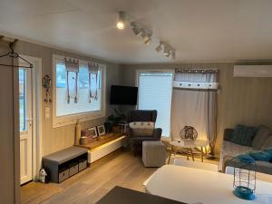 un salon avec un canapé et une chaise dans l'établissement Bujając w obłokach domek nr 22, à Gąski