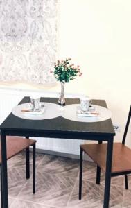 a black table with a vase of flowers and two chairs at Grb City Center - Apartment Belgrade in Belgrade +7 photos