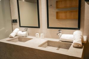 a bathroom with two sinks and two mirrors and towels at htop Amatista #htopBliss in Lloret de Mar