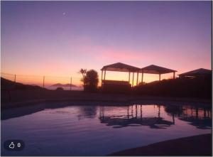 Sonnenuntergang über einem Swimmingpool mit Sonnenschirmen in der Unterkunft Acquella in Cauro
