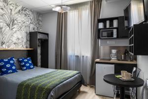 a bedroom with a bed and a table and a kitchen at Smart Appart Le Havre 97 in Le Havre