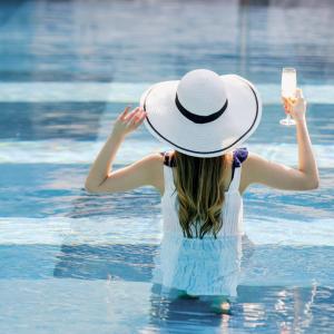une femme portant un chapeau dans l'eau avec un téléphone portable dans l'établissement Crowne Plaza Doha - The Business Park, an IHG Hotel, à Doha