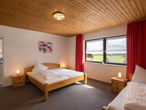 a bedroom with two beds and a window with red curtains at Apartment Eifelnatur - Haus 2-2 by Interhome in Immerath