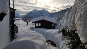 a building covered in snow next to a house at Ferienwohnungen am See _ Hinterseer in Schliersee