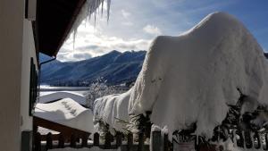 a fence covered in snow with mountains in the background at Ferienwohnungen am See _ Hinterseer in Schliersee