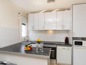 a kitchen with white cabinets and a bowl of fruit on the counter at Apartment Apartamento la Moselle by Interhome in Miami Platja