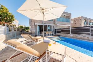 a patio with an umbrella and chairs and a pool at Villa Olea ZadarVillas in Petrcane