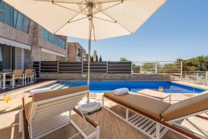 a patio with an umbrella and chairs and a pool at Villa Olea ZadarVillas in Petrcane