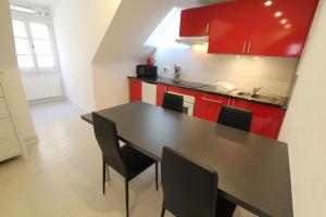 a kitchen with a black table and red cabinets at L'Appartement - Cœur de Riquewihr - 2 à 4 personnes in Riquewihr