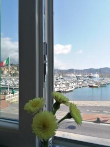 Un jarrón con flores en una ventana con vistas a un puerto. en Casa Vacanze Iris, en Imperia