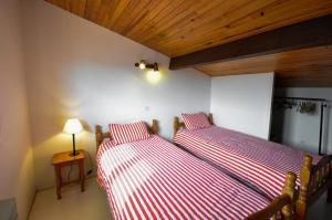 Cette chambre comprend 2 lits avec des draps rayés rouges et blancs. dans l'établissement Résidence d'Aquitaine, à Vieux-Boucau-les-Bains