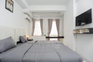 a bedroom with a large bed and a flat screen tv at RedLiving Apartment Patra Land Urbano - Alfa Rooms Tower East in Bulanbulan +30 photos