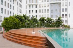 a swimming pool with stairs next to a building at RedLiving Apartment Patra Land Urbano - Alfa Rooms Tower East in Bulanbulan