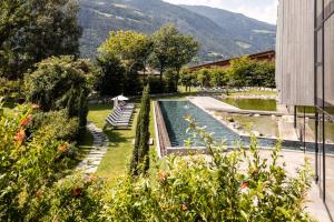 a garden with a swimming pool next to a building at Hotel Sand in Castelbello-ciardes