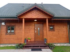 una baita di tronchi con una porta in legno e un portico di Agroturystyka Przy Siole Budy a Białowieża