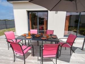 a black table with pink chairs and an umbrella at Holiday Home La Closière by Interhome in Cléder