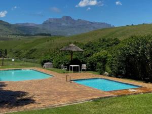 a swimming pool with a table and an umbrella at Champagne Lane Resort in Champagne Valley