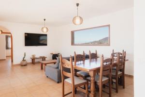 a dining room and living room with a table and chairs at Villa Upupa in La Oliva