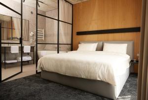 a bedroom with a large white bed and a bathroom at Air Hotel in Karmėlava