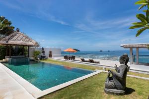 a pool with a statue of a woman sitting next to the ocean at Villa Kaniksa in Candidasa
