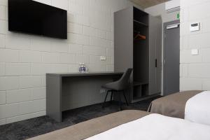 a bedroom with a desk and a television on a wall at Air Hotel in Karmėlava